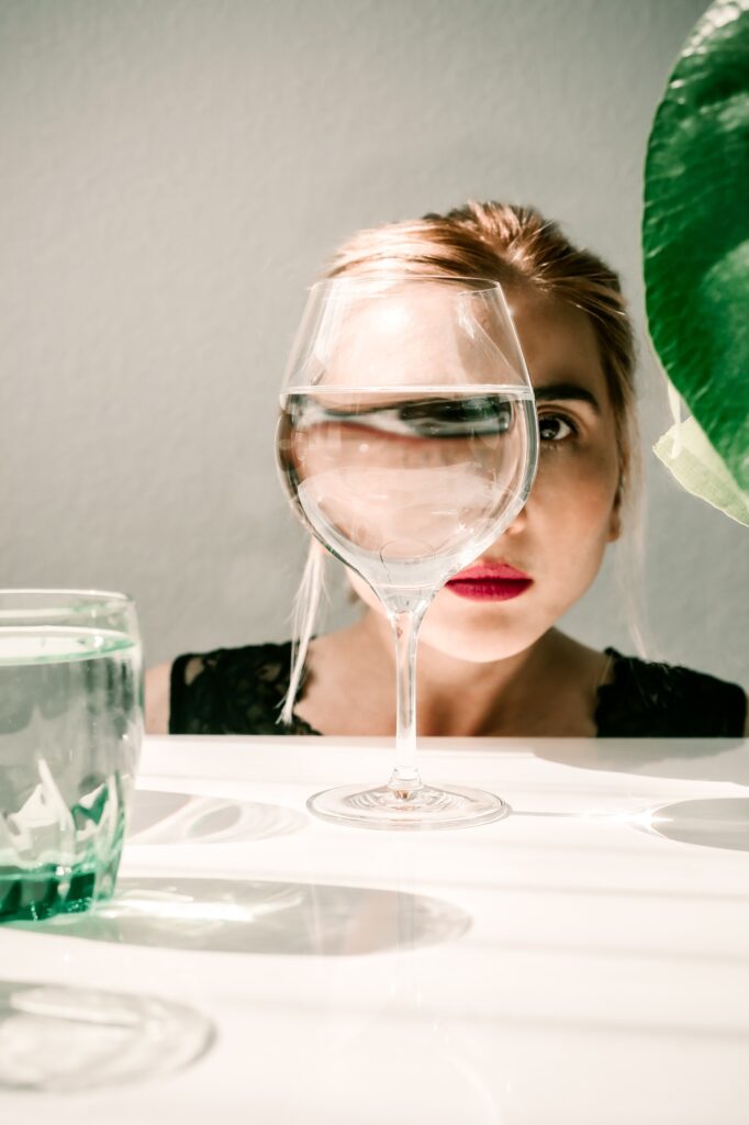 Abstract, contemporary art. Eye reflection in wine glass. Shadows on the table.