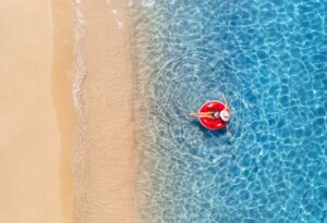 Aerial view of a young woman swimming with red swim ring