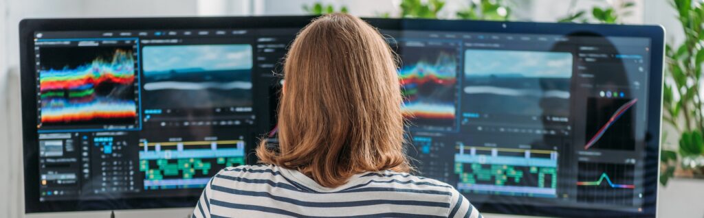 panoramic shot of editor working near computer monitors