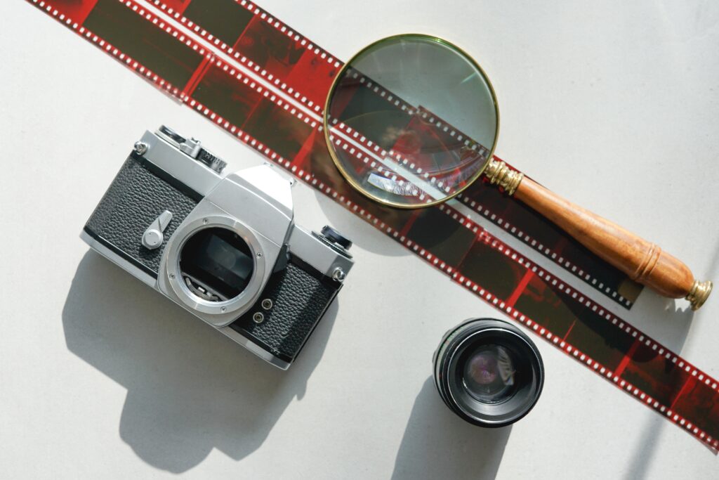 Analog photography with filmstrip old classic camera, lens and magnifying glass.