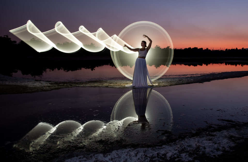 Woman posing for light painting with bright lights at sunset